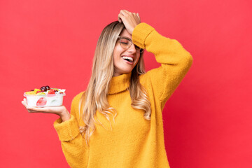 Wall Mural - Young pretty Uruguayan woman holding a bowl of fruit isolated on red background has realized something and intending the solution