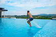 © Надежда Долгова - Happy young man jumping into swimming pool at luxury resort during summer vacation