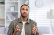 © Tetiana - Close-up photo of a young African-American man seriously talking and talking to the camera while sitting at home