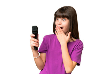 Wall Mural - Little singer girl picking up a microphone over isolated background with surprise and shocked facial expression