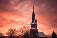The Silhouette Of A Church Steeple, Set Against A Brilliant Winter Sunset, With Hues Of Deep Orange And Pink Blending Into The Icy Blue
