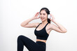 © PhugunStock - Happy slim asian woman in black workout clothes listening to music through headphones while exercising isolated with white background
