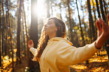 Young woman performs yoga exercises in the autumn forest, on fallen leaves. Lifestyle, meditation concept. Enjoying.