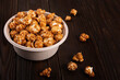 Caramelized popcorn in paper bucket on wooden kitchen table