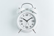 © TanyaJoy - Close-up of a white alarm clock on a white background, ten o'clock.