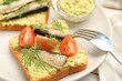 Delicious sandwiches with sprats, tomatoes, dill and avocado puree served on white table, closeup