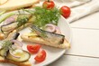 Delicious sandwiches with sprats, pickled cucumber, onion and dill served on white wooden table, closeup