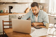 © Geber86 - Worried young Caucasian man going over his bills and home finances in the morning in the kitchen