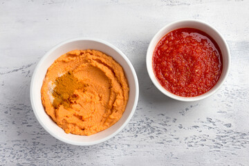 Ingredients for homemade lentil pancakes: fresh tomato sauce with spices, ground red lentils and spices - turmeric, paprika, salt on a light gray background