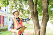 man with hard hat standing in front of a tree inspect