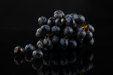 Wall Mural - A bunch of dark blue grapes on a black background with highlights and reflection