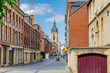 Amiens cityscape, narrow pedestrian street with traditional buildings and Belfry of Amiens beffroi bell tower in old historical city centre, Somme department, Hauts-de-France Region, Northern France