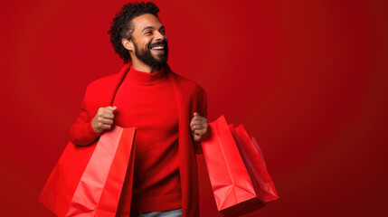 Wall Mural - Happy smiling man holding shopping bags on red background