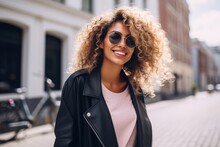 woman with curly hair in the city wearing sunglasses