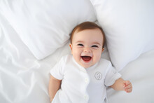 A Photo Of A Baby Lying On A White Bed Sheet