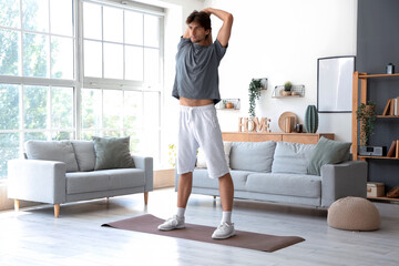 Handsome young man in sportswear doing exercises at home