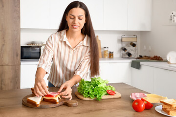 Canvas Print - Young woman making tasty sandwich in kitchen