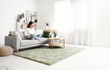 © Pixel-Shot - Beautiful young Asian woman with laptop sitting on sofa in living room