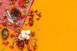 © Pixel-Shot - Diya lamp with marigold flowers, tea and plate of treats on orange background. Divaly celebration