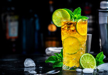 Dark And Stormy Cocktail Drink With Dark Rum, Ginger Ale, Lime And Ice With Bottles, Black Bar Counter Background