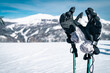 Close up of ski gloves on ski poles on top of a mountain range covered with bright white snow. Winter Alpine scenery with sport equipment.