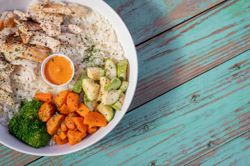 Wall Mural - Chicken dish with healthy rice, with boiled vegetables, on a blue table.