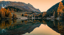 Autumn Colours And Sunrise With Reflections In Calm Mountain Lake In The Swiss Alps