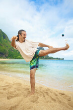A Man Plays With His Hackey Sack In The Sand At The Water's Edge; Hawaii United States Of America