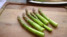Six Asparagus Shoots On Wooden Cutting Board. Handheld, Dolly, Slow Motion
