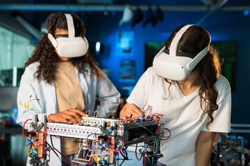 Wall Mural - Two young women in VR glasses doing experiments in robotics in a laboratory