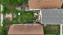 Abandoned And Desolate Row House In Urban City. Aerial Descending Shot Above Overgrown Yard And Home With Destroyed Windows And Walls.