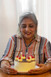 © IndiaPix - A MATURE ADULT WOMAN SMILING AND LOOKING AT BIRTHDAY CAKE
