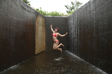 Wall Mural - Pretty Asian female in a swimsuit is jumping happily and relaxing at the spillway.