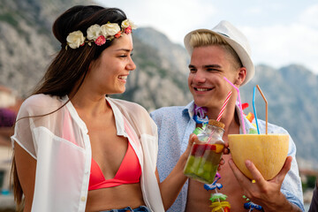 Wall Mural - Happy multiethnic young couple in love are on a date, enjoying cocktails on the beach