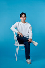 Wall Mural - Photo of young guy smiling sitting chair empty space isolated blue color background