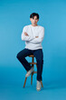 © makistock - handsome young man sitting on the chair, isolated on blue background