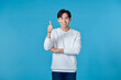 © makistock - portrait young Asian man thumbs up or ok hand sign on blue background