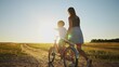 © maxximmm - mom teaches son to ride a bike. happy family childhood dream concept. mom and little son learn to ride a bike silhouette in the park in sunlight nature. happy family goes in for sports outdoors