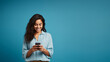 © overrust - Woman looks at her cell phone with a smile isolated on blue background
