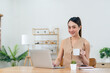 © Natee Meepian - Young asian woman working on laptop in the home desk and sit at table rest drink coffee