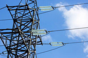 High voltage tower with electrical voltage wires isolates close-up against the background of clouds. Energy industry.