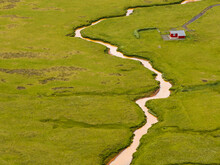 Aerial View Of A Small House Along The River In A Green Grass Valley, Hvolsvollur, Southern Region, Iceland.