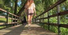 Athletic Woman Walking Through City Park With Small Bag After Workout, Back View, Follow, Gimbal
