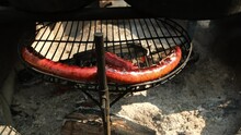 Slow Motion Of Sausage Being Barbecued Or Grilled Over Fire Pit While Moving Camera Right To Left.