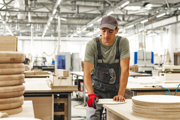 Wall Mural - Young carpenter making wood furniture while working in joinery