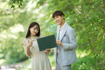 A loving couple are taking wedding photos with green boards outdoors for their wedding.