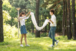 © Dialogue Frame - A young couple using a large towel to have fun in a forested park