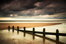 A Fence Submerged In The Water At The Coast With Storm Clouds Overhead; Berwick Northumberland England