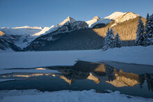 Early Morning Sunlit Snow Covered Mountains Reflecting In A Lake With Deep Blue Sky; Lake Louise Alberta Canada