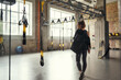 © Friends Stock - Morning workout. Back view of young athletic woman carrying her sport bag and looking aside while standing at empty gym.